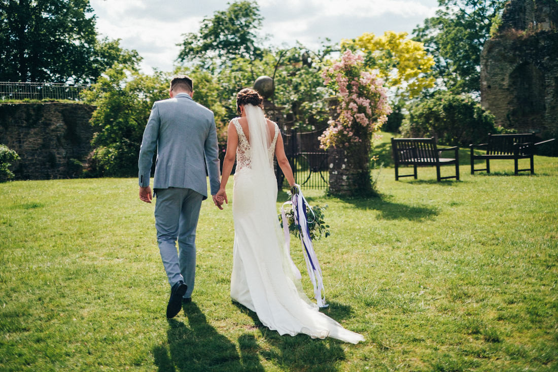 004 CANDID PORTRAIT OF BRIDE AND GROOM WALKING IN BEAUTIFUL DRESS USK CASTLE WEDDING PHOTOGRAPHY
